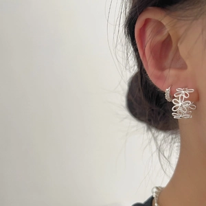 Exquisite S925 silver lace hollow flower earrings worn by a model in a stylish layered look
