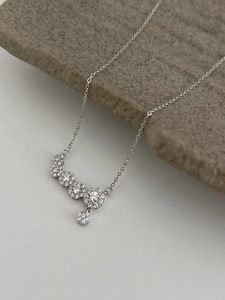 Detailed view of silver necklace with cubic zirconia clusters on stone background