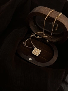 Detail of vintage brushed gold floral pendant with sparkling crystals and wooden gift box