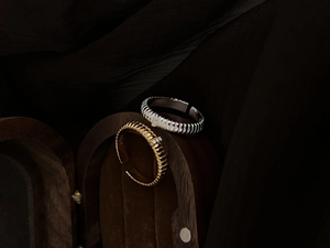 Macro shot of S925 silver rings with striped texture and crystal inlay on wood