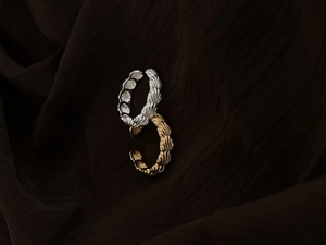 Détails de bagues coquillage or et argent avec motifs radiaux sur tissu brun