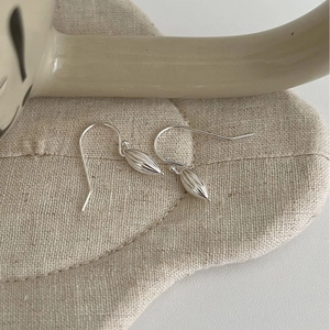 Elegant S925 sterling silver shell earrings with textured drops on minimalist fabric