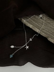 Detail of S925 sterling silver starfish necklace with pearl and blue gemstone charms