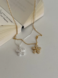 Detailed macro view of gold and silver five-petal flower necklaces on a vintage book