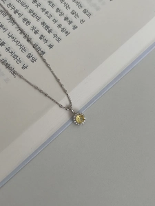 Vue macro du collier en argent avec pierre jaune ronde et halo de zircons blancs