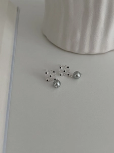 Close-up of silver hollow floral earrings with black stones and dark grey pearls