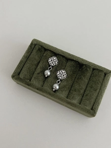 Close-up of vintage grey pearl earrings with silver flower detail in green velvet box