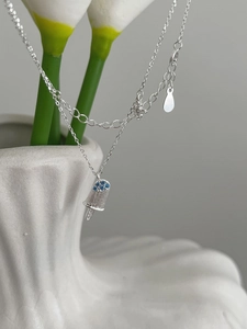 Macro detail of silver popsicle pendant with blue zircon stones and brushed texture