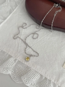Gros plan sur collier en argent S925 avec pendentif en zircon olive sur dentelle blanche