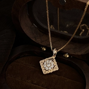 Vintage gold hollow pillow necklace with sparkling crystal clusters on dark wood tray