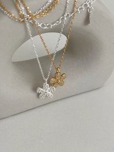 Close-up of elegant floral necklaces in silver and gold with sparkling pavé petals