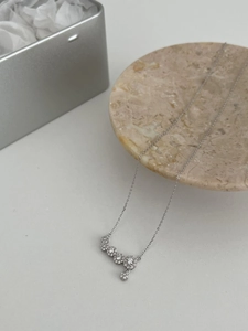 Detail of silver necklace featuring four zircon flower pendants on a marble tray