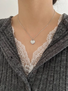 Primo piano di collana cuore in argento 925 con ciondolo a stella indossata su maglieria