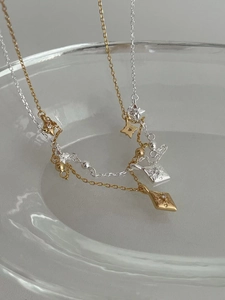 Macro de colliers à pendentif étoile en or et argent posés sur du verre