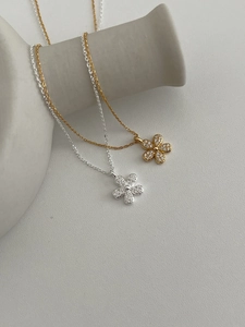 Close-up of gold and silver flower necklaces with sparkling crystals on minimalist stands