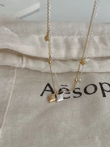 Détail d'un collier multicouche avec pendentifs étoile et soleil sur une pochette