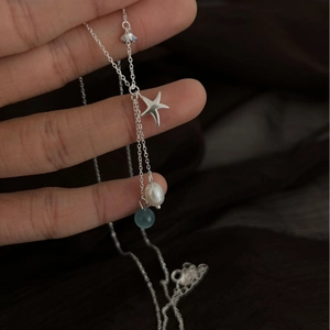S925 silver necklace with starfish pendant, pearl and blue gemstone on silk background