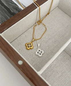 Dettaglio del ciondolo a quadrifoglio opaco con finiture in oro e argento spazzolato