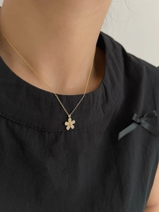 Detail of a sparkling gold flower pendant with pave diamonds on a delicate chain
