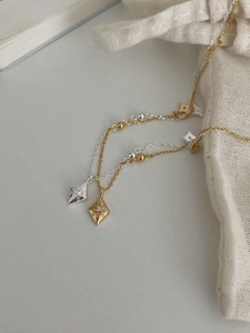 Détails des pendentifs losanges dorés et argentés avec motifs étoilés sur chaînes à billes