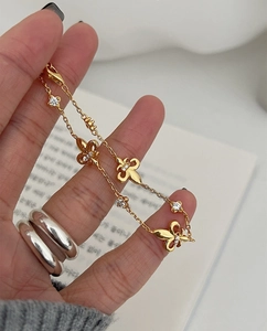 Detail of gold fleur-de-lis bracelet with sparkling crystals on a woman's hand