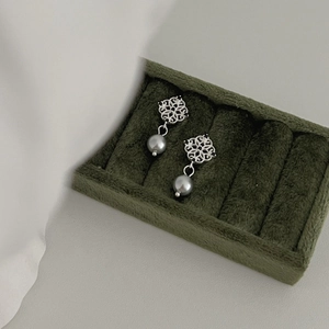 Elegant grey pearl drop earrings with floral silver studs on a velvet jewelry box