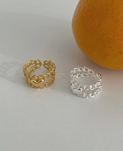 Detail of silver and gold double-layer chain rings with heart charms on grey background
