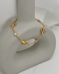 Macro detail of gold butterfly bracelet with white zircon stones on a gray vase display