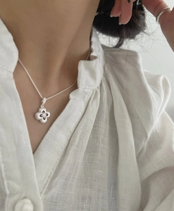 Dettaglio della collana in argento S925 con quadrifoglio e finitura satinata su lino