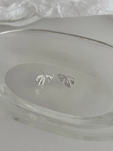 Détail de boucles d'oreilles nœud en argent avec gravures horizontales sur plateau en verre