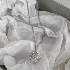 Collana in argento 925 con ciondolo a cuore spazzolato e zirconi su carta bianca stropicciata