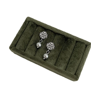 Elegant grey pearl drop earrings with silver hollow flower top on green velvet display