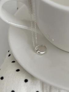 Gros plan d'un collier pendentif en V minimaliste en argent S925 sur une tasse en céramique
