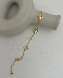 Detailed macro view of gold fleur-de-lis bracelet with elegant micro-pave white crystals