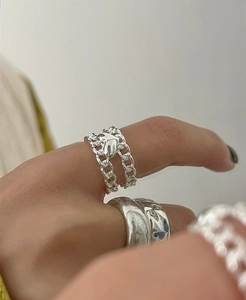 Detail of silver double-layer chain ring with heart and hammered wide band on finger