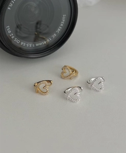 Macro shot of silver and gold heart-shaped hoop earrings set with small clear zircons