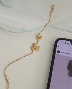 Macro detail of gold clover bracelet with sparkling zircons on blue fabric backdrop
