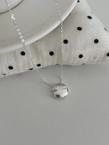 Gros plan du collier en argent avec pendentif géométrique et finition miroir polie