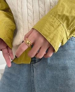 Close-up of golden double-layered heart chain ring on finger with lifestyle outfit
