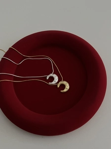 Macro detail of hammered crescent moon necklaces in gold and silver on red velvet