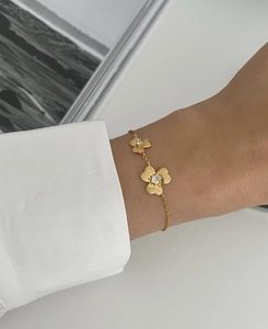 Detailed view of gold clover bracelet featuring brushed metal petals and inlaid crystal
