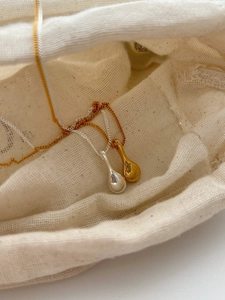 Macro detail of gold and silver solid water drop pendants on minimalist necklaces