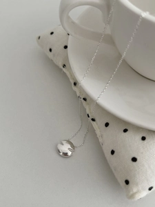 Gros plan d'un collier en argent S925 avec pendentif rond irrégulier en forme de V