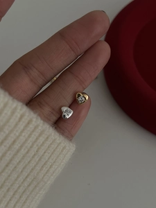 Gros plan de mini boucles d'oreilles cœur en or et argent avec pierres de zircon