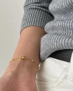 Detail of a delicate gold chain bracelet with a sparkling crystal butterfly charm on wrist