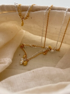 Detailed macro shot of gold and silver teardrop pendant necklaces on linen fabric
