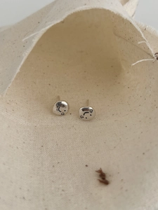 Macro di orecchini a lobo vintage con faccina sorridente in argento su sacchetto beige