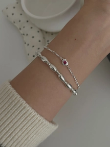 Detail of silver beaded bracelet and red heart pendant necklace on model wrist