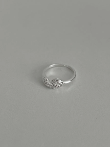 Vue détaillée du design de nœud argenté et de la texture métallique torsadée de la bague