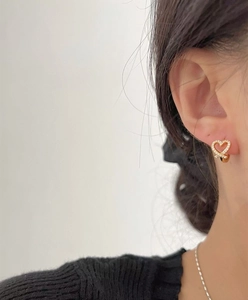 Close-up of heart-shaped gold stud earring with white zircons on female ear